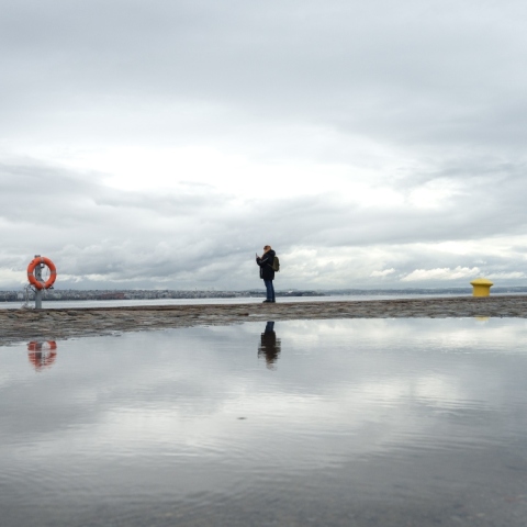 Γυναίκα στέκεται στην παραλία της Θεσσαλονίκης με συννεφιασμένο καιρό