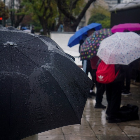 Πολίτες με ομπρέλες προστατεύονται από τη βροχή