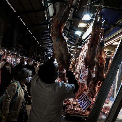 Στιγμιότυπο από κρεοπωλείο όπου εργαζόμενος ξεκρεμά αρνί από τα τσιγκέλια