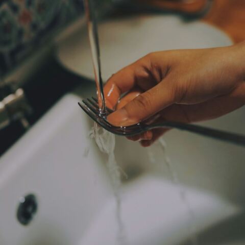 Χέρι ξεπλένει πιρούνι με νερό