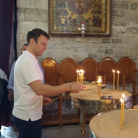 Ο Στέφανος Κασσελάκης ανάβει κεράκι σε εκκλησία κατά τη διάρκεια της περιοδείας του στα νησιά
