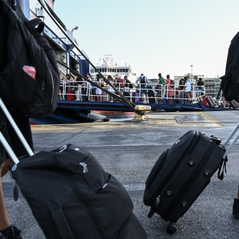 Πολίτες με βαλίτσες ετοιμάζονται για τον απόπλου από το λιμάνι του Πειραιά