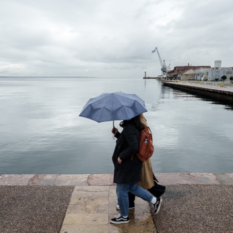 Κόσμος περπατάει έπειτα από βροχόπτωση στην παλιά παραλία της Θεσσαλονίκης