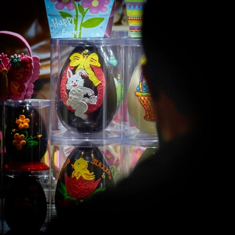 Σκιά ατόμου στα δεξιά του φακού που κοιτά βιτρίνα με σοκολατένια αυγά με φιγούρες από κινούμενα σχέδια