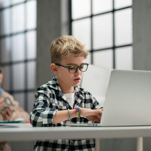 Μαθητής καθισμένος στο θρανίο του κάνει χρήση λάπτοπ