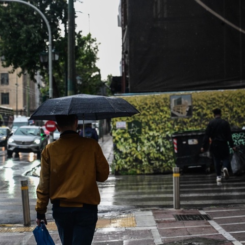 Άτομο με ομπρέλα προστατεύεται από μπόρα στο κέντρο της Αθήνας