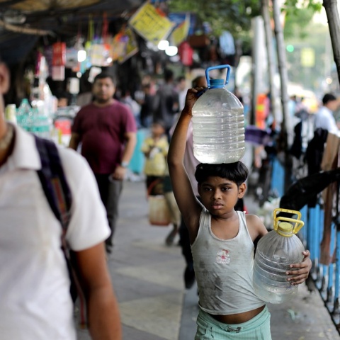 Παιδί στην Ινδία μεταφέρει μποτίλιες με νερό στο χέρι και στο κεφάλι του