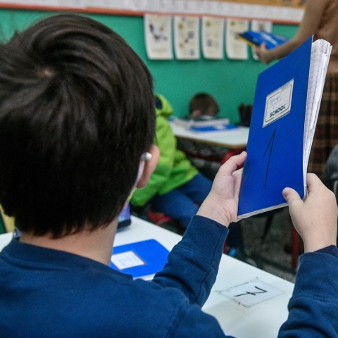 Παιδί με το μπλε τετράδιό του ανά χείρας στην τάξη του