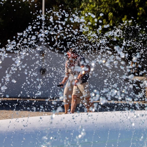Πολίτες περπατούν πίσω από συντριβάνι