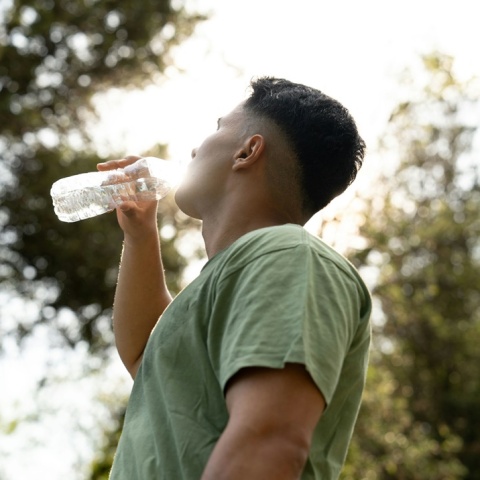 Άνδρας που έχει ιδρώσει από τιος υψηλές θερμοκρασίες, δροσίζεται πίνοντας νερό