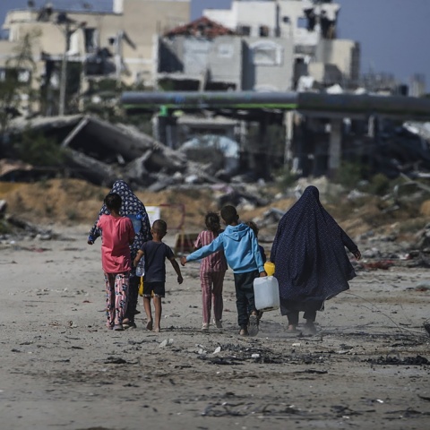 Παιδιά περπατούν δίπλα από βομβαρδισμένα κτίρια στη Γάζα