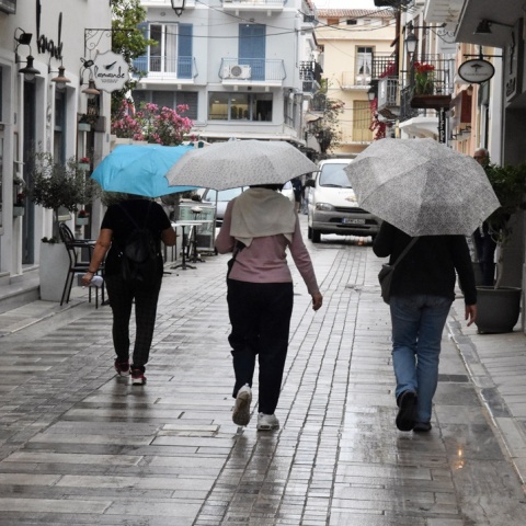 Άτομα κρατούν ομπρέλα ενώ περπατούν στον δρόμο
