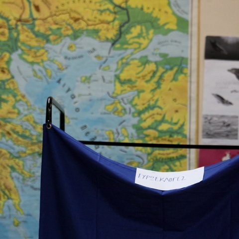 Παραβάν σε εκλογικό τμήμα με φόντο χάρτη της Ελλάδας