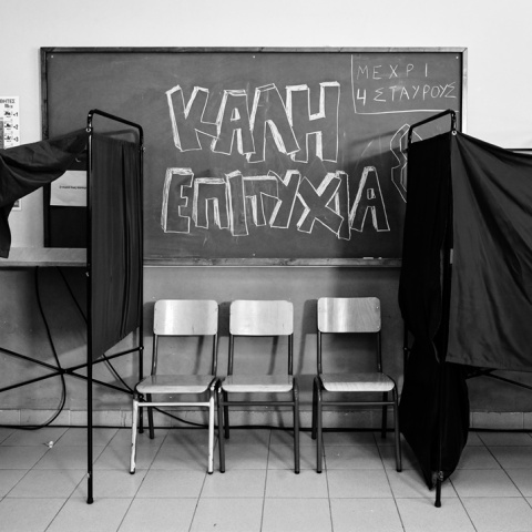 Ασπρόμαυρη φωτογραφία από εκλογικό κέντρο σε πίνακα στον οποίο γράφει «Καλή Επιτυχία»