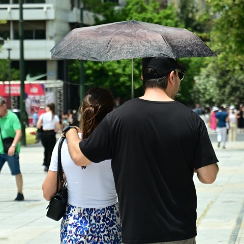 Ζευγάρι κρατά ομπρέλα για να προστατευτεί από τις ακτίνες του καυτού ήλιου