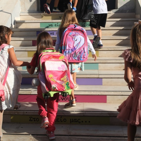Μαθητές με τις τσάντες τους στην πλάτη ανεβαίνουν τα σκαλιά για να μπουν στο σχολείο τους