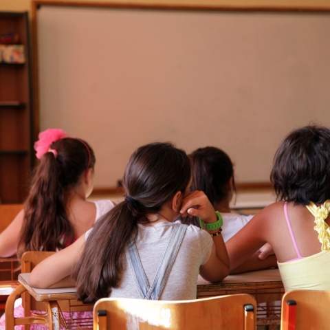 Μαθήτριες κάθονται στο θρανίο τους μέσα στη σχολική αίθουσα, με πλάτη στον φακό