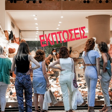 Κυρίες μπροστά από βιτρίνα καταστήματος με προϊόντα σε έκπτωση