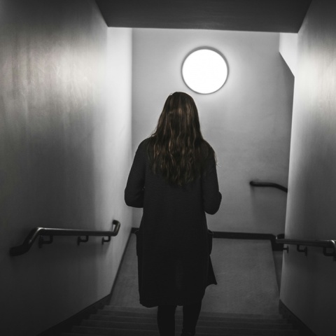 Γυναίκα περπατά σε σκοτεινό διάδρομο - Εικόνα που παραπέμπει σε κακοποίηση και ενδοοικογενειακή βία