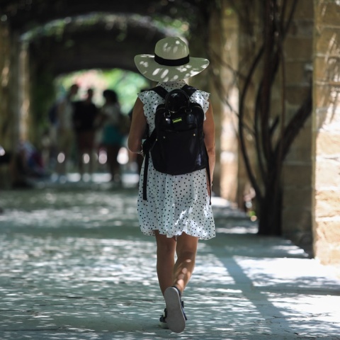 Γυναίκα με καπέλο και καλοκαιρινά ρούχα περπατά στον Εθνικό Κήπο