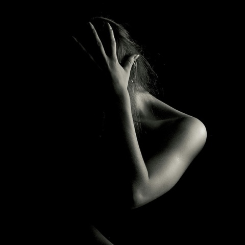 Γυναίκα στο ημίφως που προστατεύει το πρόσωπο και το σώμα της από πιθανή απειλή