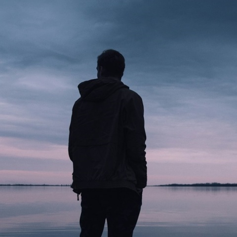 Νεαρό άτομο κοιτά τον ορίζοντα γυρισμένο πλάτη στον φακό