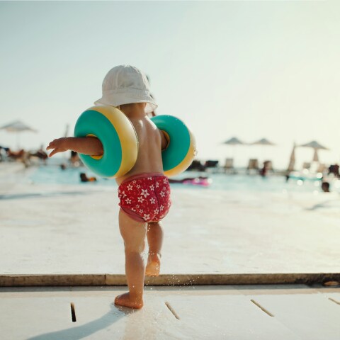 Παιδάκι με μπρατσάκια σε εξέδρα οργανωμένης παραλίας έχει την πλάτη στον φακό