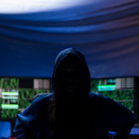 Άτομο με κουκούλα στο σκοτεινό δωμάτιο