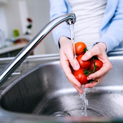 Άτομο πλένει ντοματίνια σε βρύση