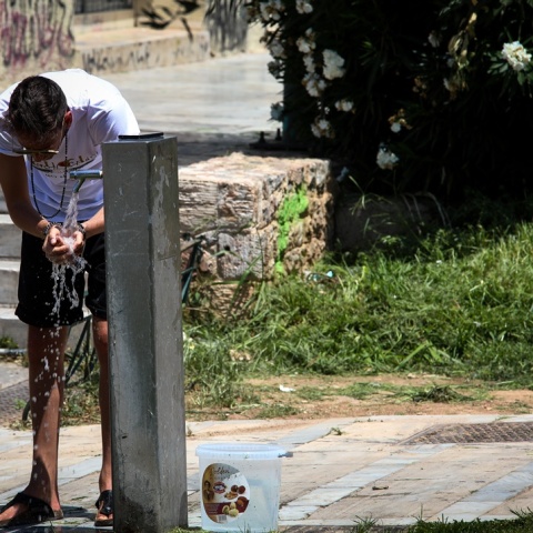 Άτομο που δροσίζει λίγο το πρόσωπό του με νερό από βρύση σε δημόσιο χώρο
