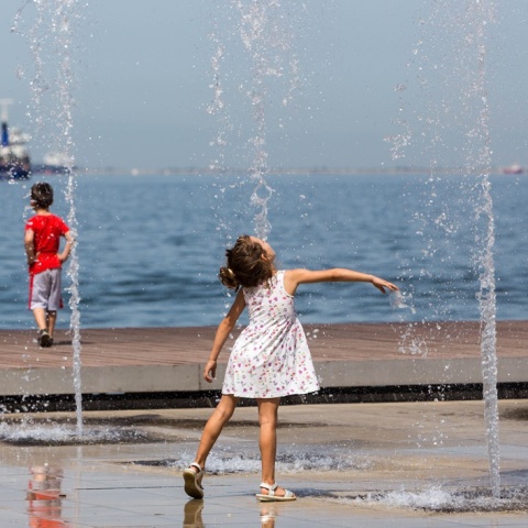 Παιδί παίζει με το νερό στο σιντριβάνι εν μέσω καύσωνα