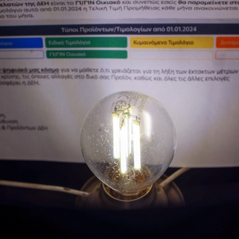 Τιμολόγιο ηλεκτρικού ρεύματος με μία αναμμένη λάμπα μπροστά