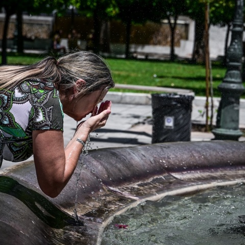 Γυναίκα δροσίζεται ρίχνοντας νερό στο πρόσωπό της από το σιντριβάνι στο Σύνταγμα