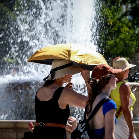 Πολίτες με ομπρέλες προστατεύονται από τον καύσωνα