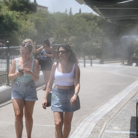 Γυναίκες στο κέντρο της Αθήνας παιρνούν από spot δροσιάς καταστήματος εστίασης