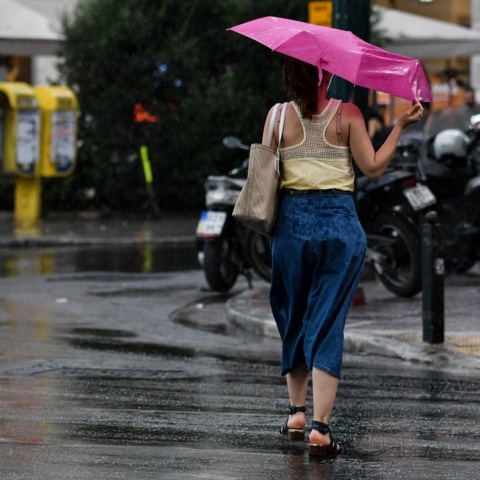 Κοπέλα κρατά ομπρέλα για να μην βραχεί από καλοκαιρινό μπουρίνι
