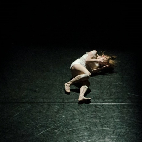 Γυναίκα σε εμβρυακή στάση σε σκοτεινό δωμάτιο με φως να πέφτει στο σώμα της