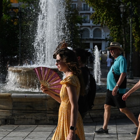 Γυναίκα περπατά στο κέντρο της Αθήνας κρατώντας τη βεντάλια της