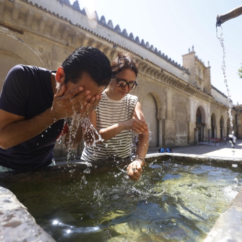 Γυναίκα και άνδρας δροσίζονται ρίχνοντας στο πρόσωπό τους νερό σιντριβανιού