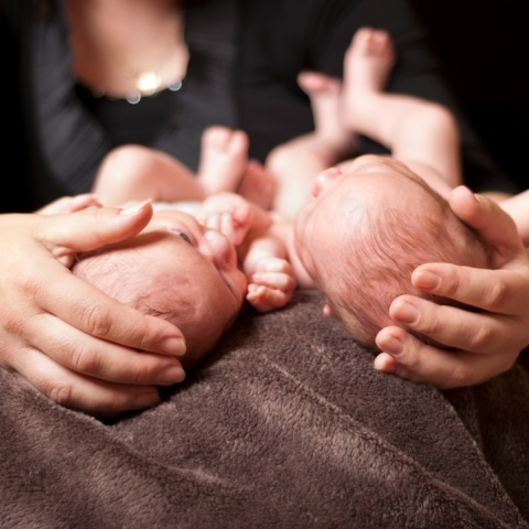 Δίδυμα παιδάκια στην αγκαλιά ατόμου