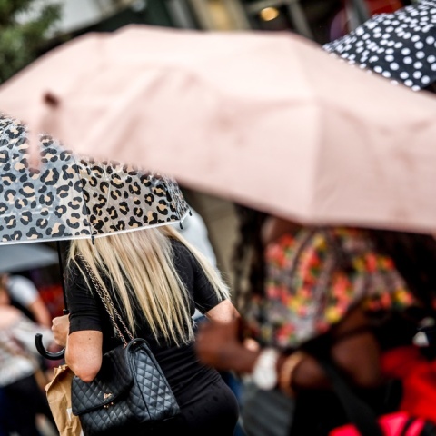 Άτομα προστατεύονται από τη βροχή με ομπρέλες