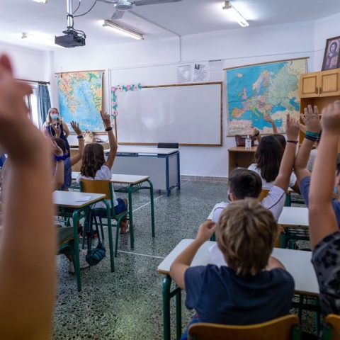 Παιδιά με υψωμένα τα χέρια τους για να πουν μάθημα σε σχολική αίθουσα