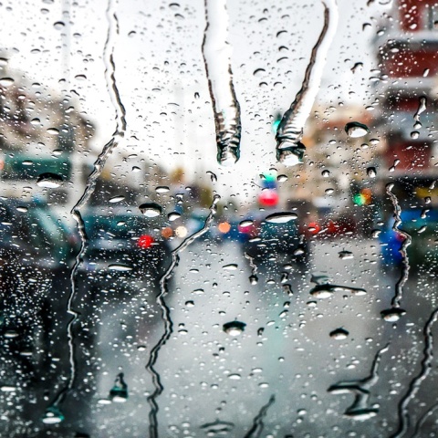 Σταγόνες βροχής σε τζάμι αυτοκινήτου όπου φαίνονται τα προστινά οχήματα