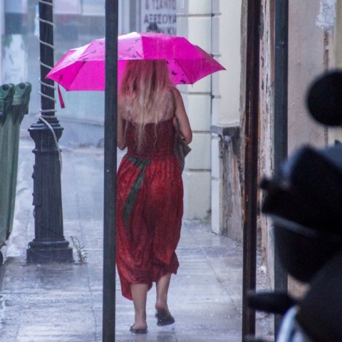 Γυναίκα προστατεύεται από τη βροχή με ομπρέλα