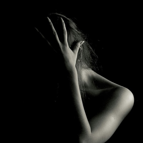 Γυναίκα που κρύβει με το χέρι της το πρόσωπό της σε στάση άμυνας