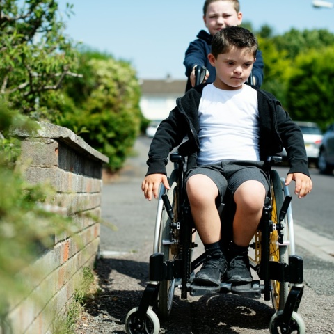 Παιδί οδηγεί το καρότσι παιδιού με κινητικές δυσκολίες