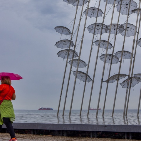 Γυναίκα κρατά ομπρέλα ενώ περπατά στην παραλία της Θεσσαλονίκης