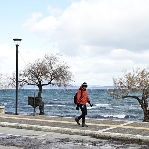 Άτομο περπατά δίπλα στη θάλασσα εν μέσω κρύου με μπουφάν και σκουφί