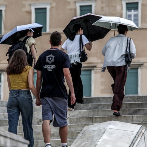 Πολίτες, άλλοι με ομπρέλες και άλλοι χωρίς, ανεβαίνουν τα σκαλάκια της πλατείας Συντάγματος