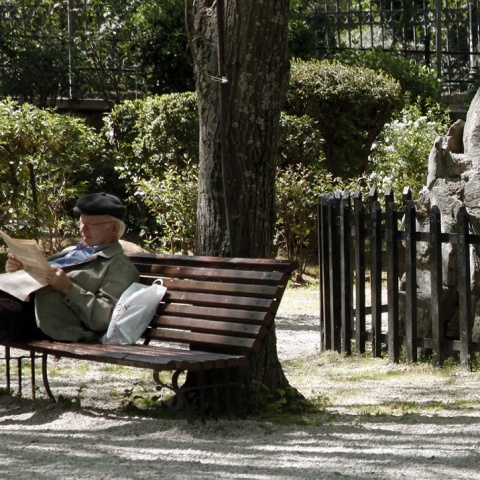 Συνταξιούχος διαβάζει εφημερίδα σε παγκάκι